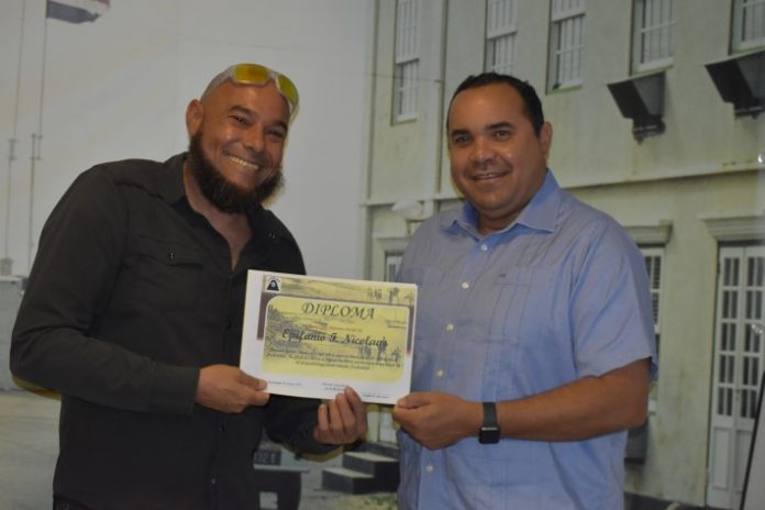 Jason risibiendo su diploma serka gezaghebber Rijna despues di a terminá un kurso intensivo, mará na un eksámen di FuHiKuBo.